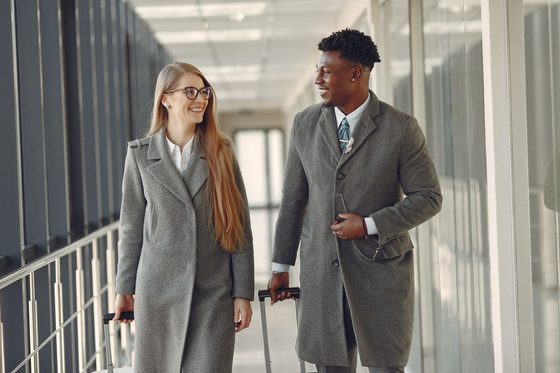 Two business travelers walking through an airport terminal with luggage