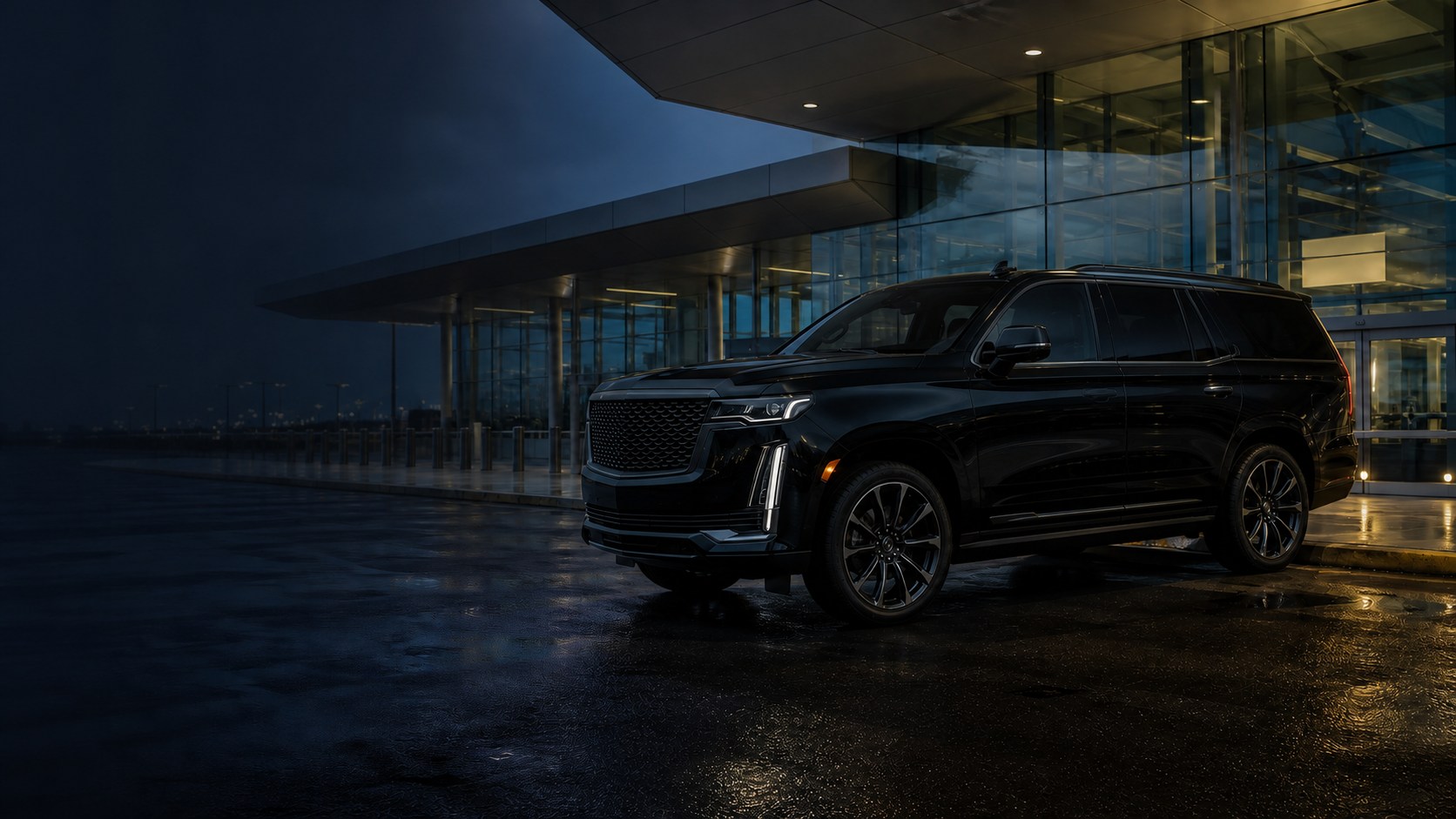 Black executive SUV outside an airport terminal at night